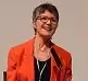 Small photo of Dr Meredith Doig, smiling, wearing red jacket, in front of microphone