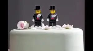 Two male lego figures on top of a wedding cake.